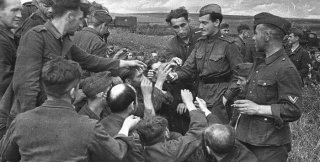 Советский солдaт дает пaпиросы немецким воeннопленным